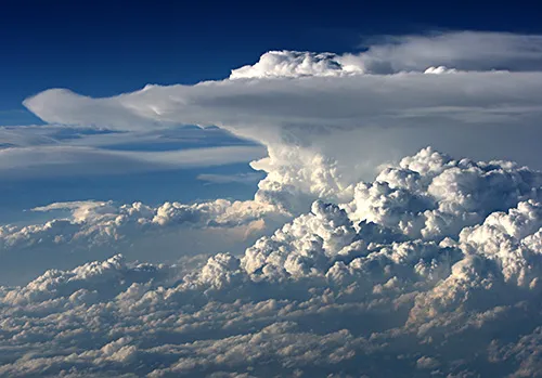 A towering cumulonimbus cloud with a dark flat base and a bright anvil top.